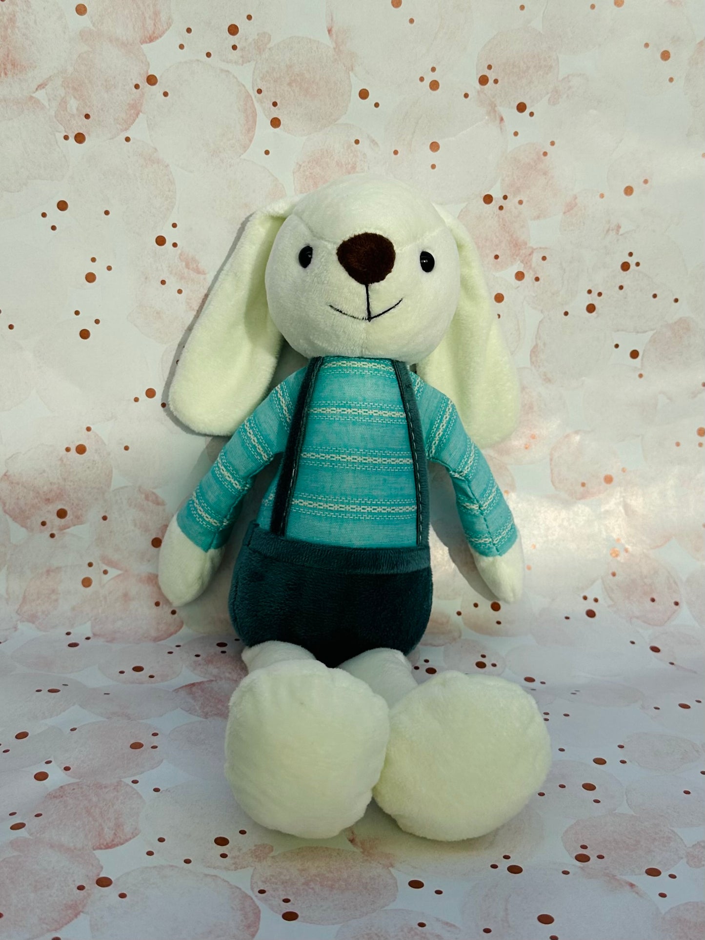 Stuffed animal toy with a blue sweater on a patterned background
