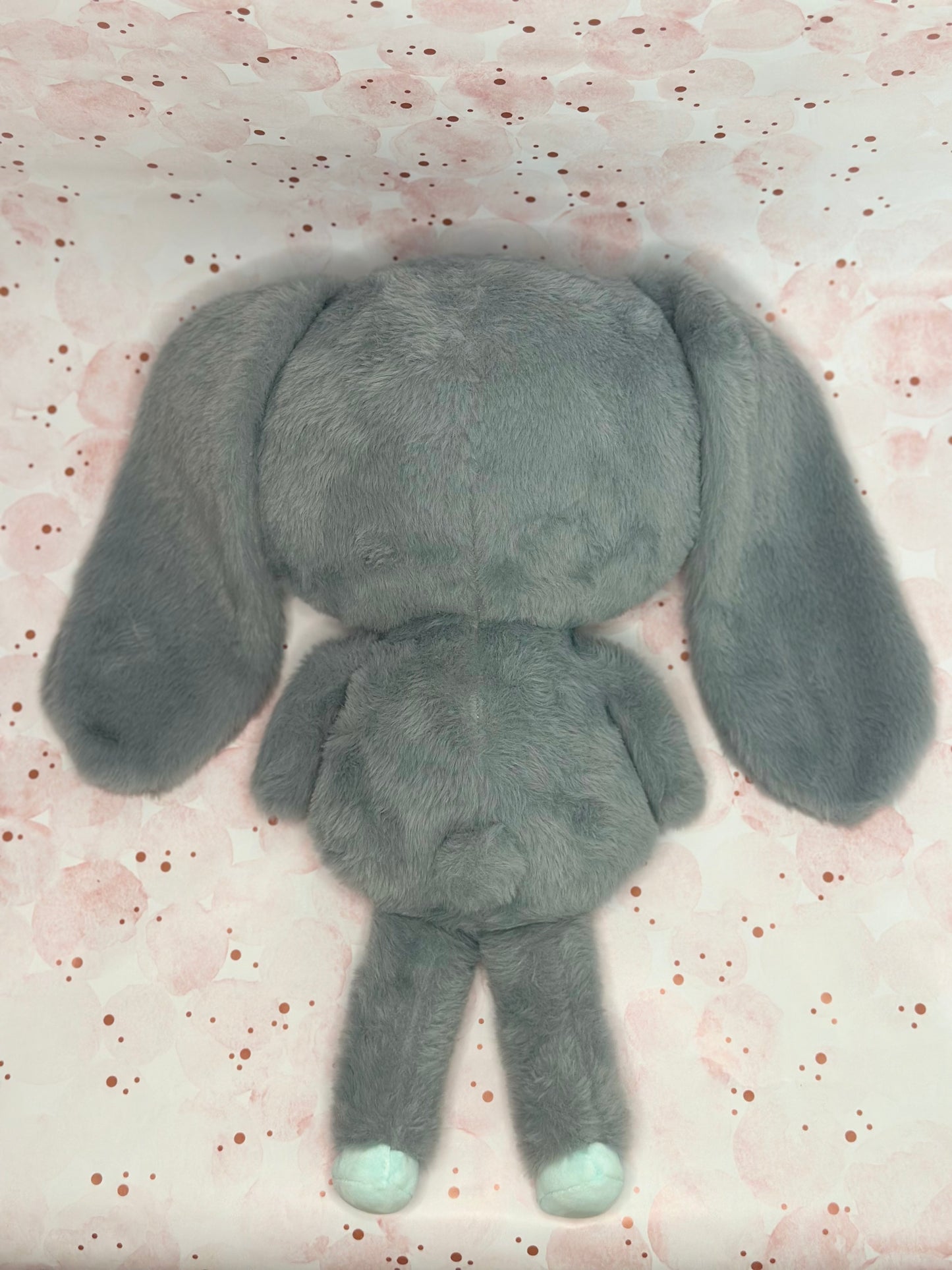 Gray plush toy bunny on a pink background