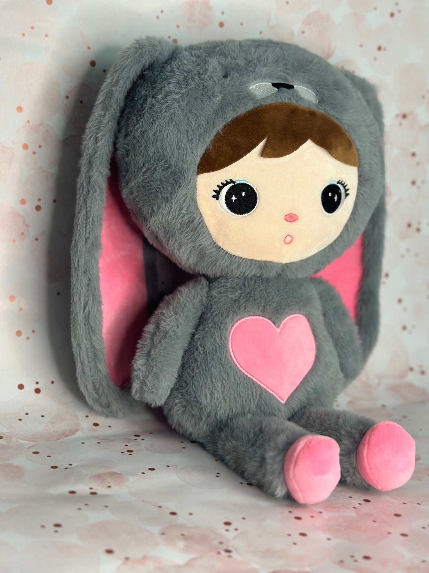 Stuffed Animal with a gray hood and pink heart on a light background
