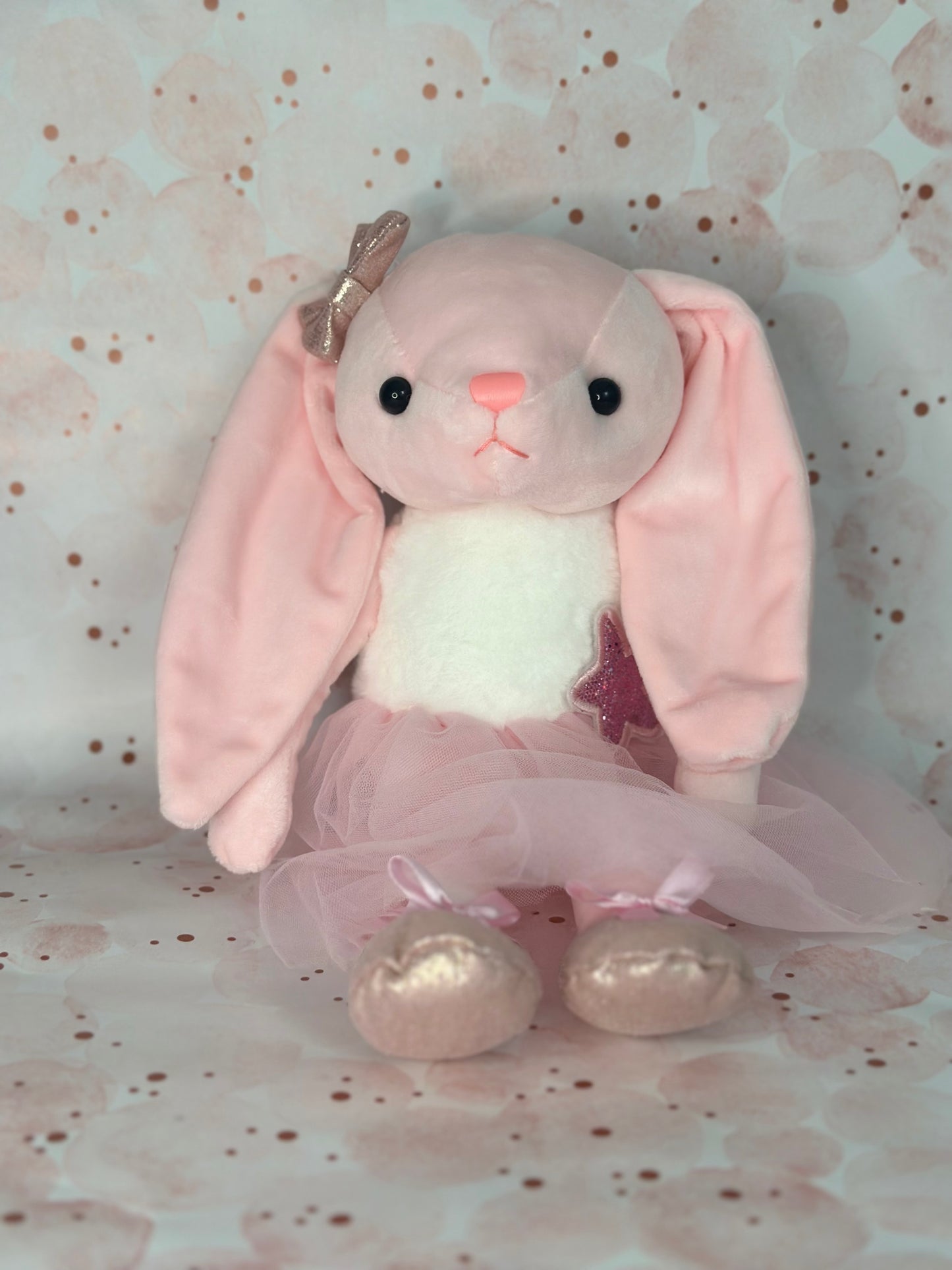 Pink plush bunny toy with a bow on a floral background