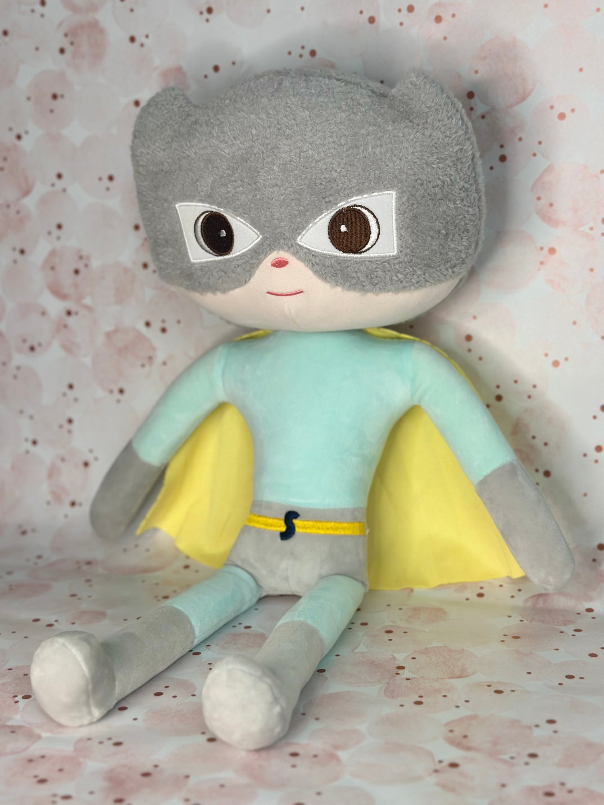 Plush toy with gray hair, light blue shirt, and gray pants on a patterned background