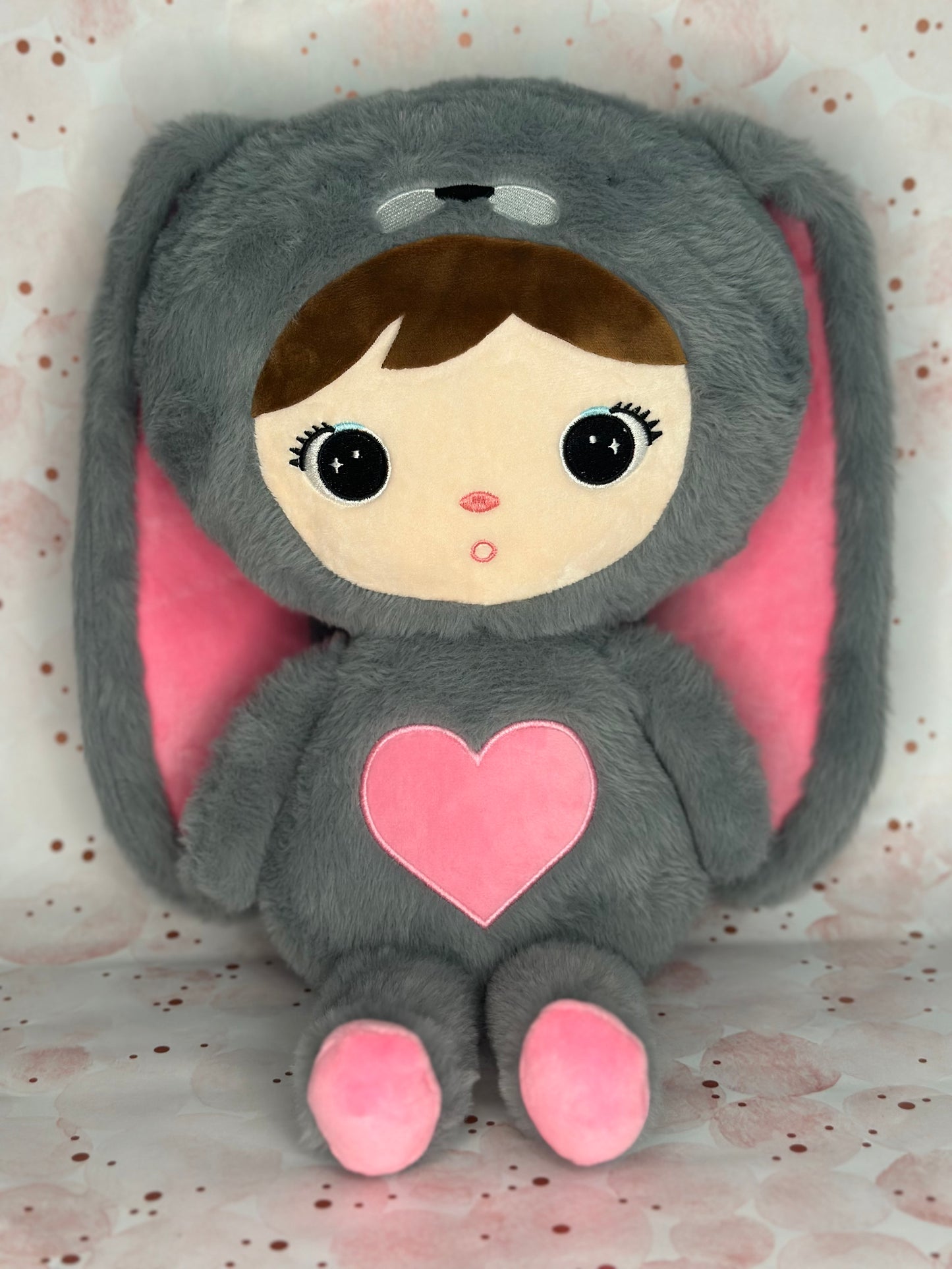 Plush toy with a gray bunny costume and pink heart on a light background
