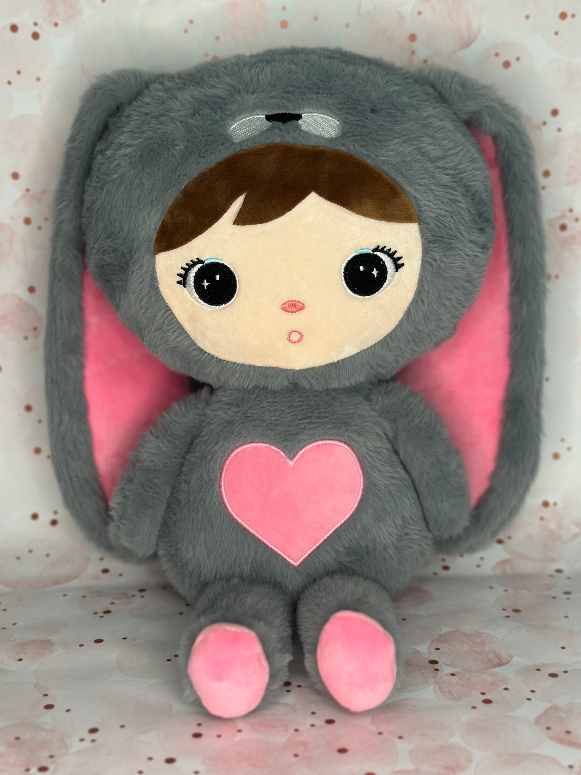 Plush toy with a gray bunny costume and pink heart on a light background