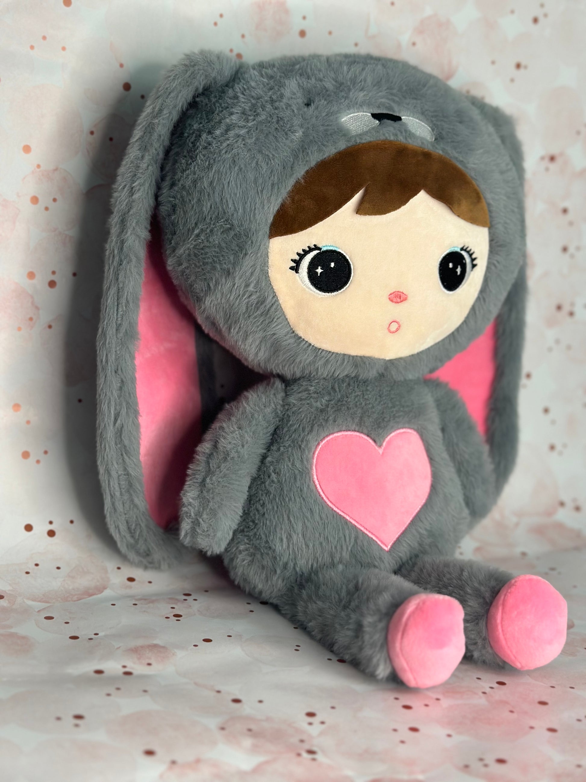 Stuffed Animal with a gray hood and pink heart on a light background