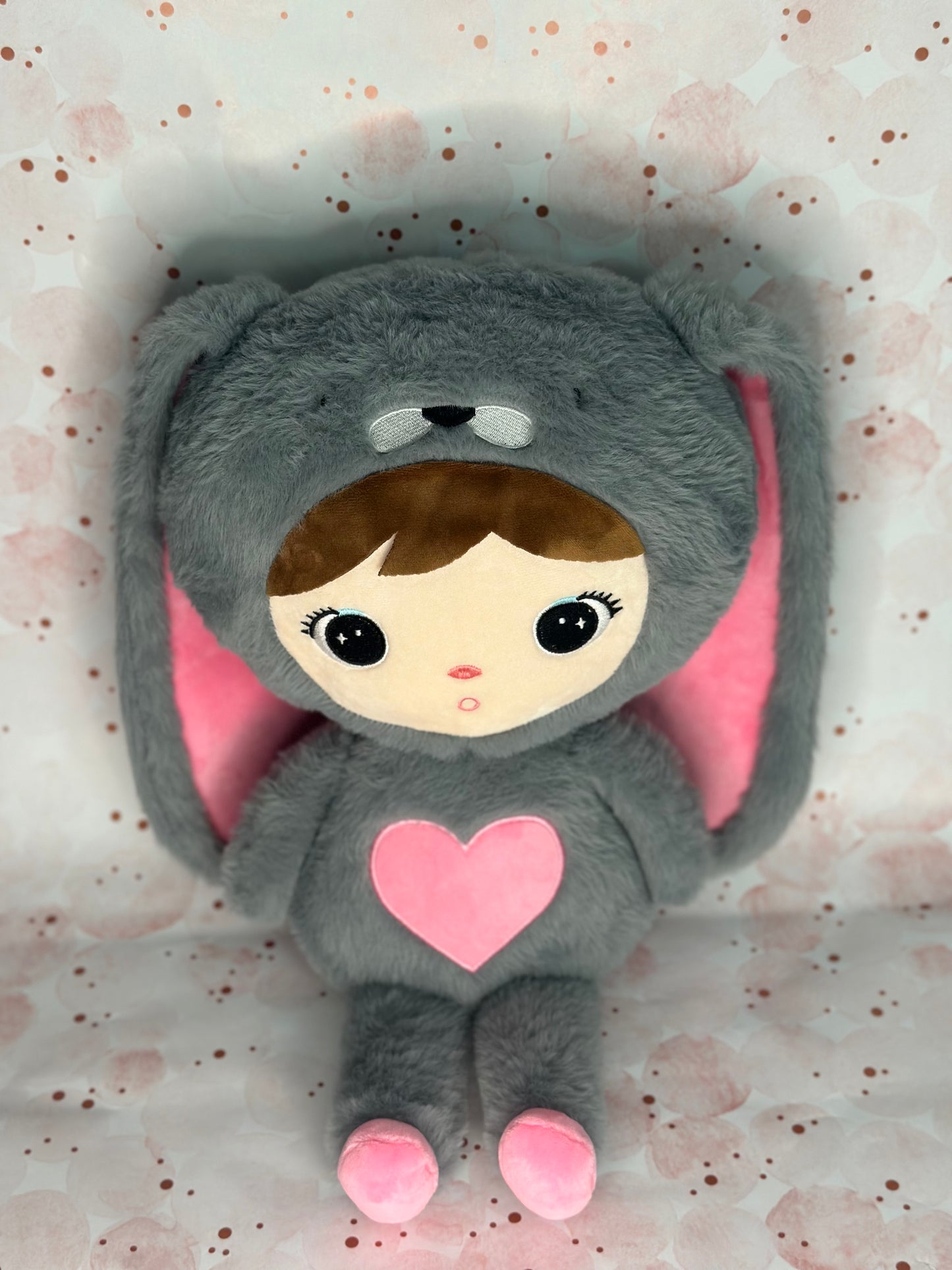 Plush toy in a gray costume with pink heart and ears on a light background