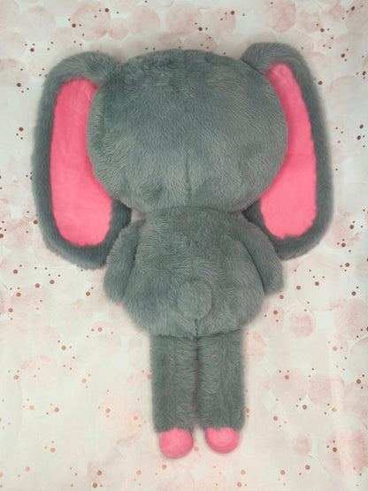 Gray plush bunny toy with pink ears on a light pink background