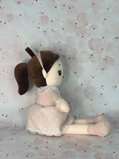 Stuffed toy doll in a dress sitting on a floral-patterned surface