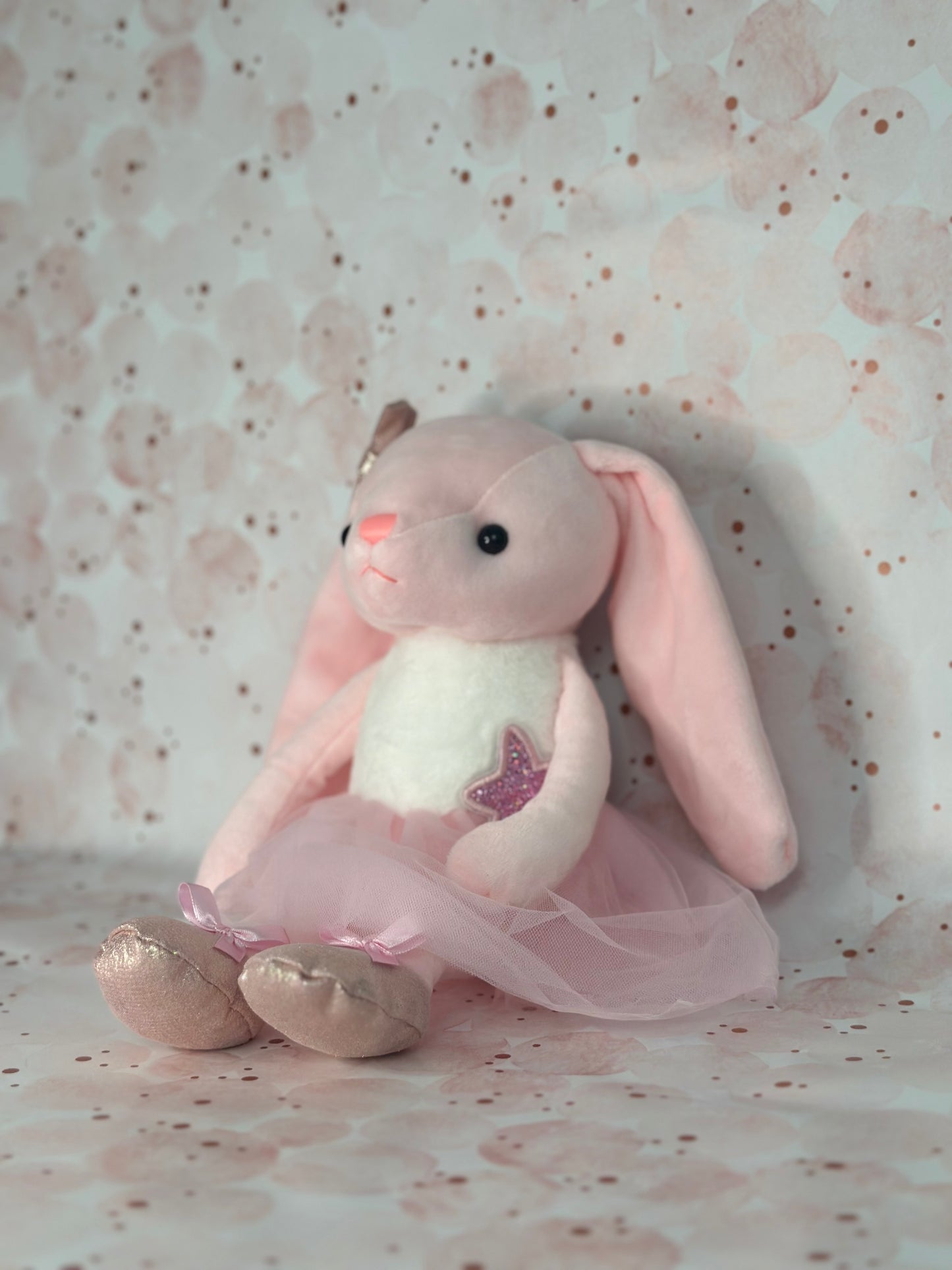 Plush toy rabbit in a pink outfit on a patterned background