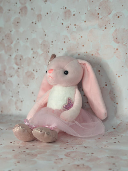 Plush toy rabbit in a pink outfit on a patterned background