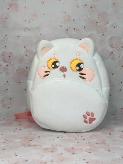 White cat-shaped plush toy with pink accents on a light pink background